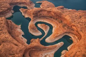 Aerial view of a winding river surrounded by red rocks.