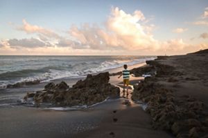 Boy walks between rocks on beach.
