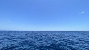 A view looking over the small waves in the huge ocean with water as far as can be seen.