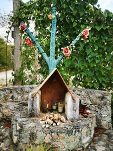 Beautiful spiritual ritual is set up outside, showing a small house with candles and flowers.