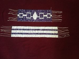 Two beaded art belts are featured on a hard surfact. 