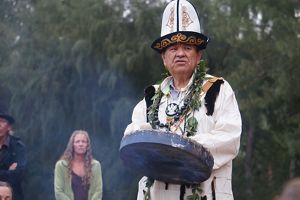 A man wearing native regalia leads a ceremony.