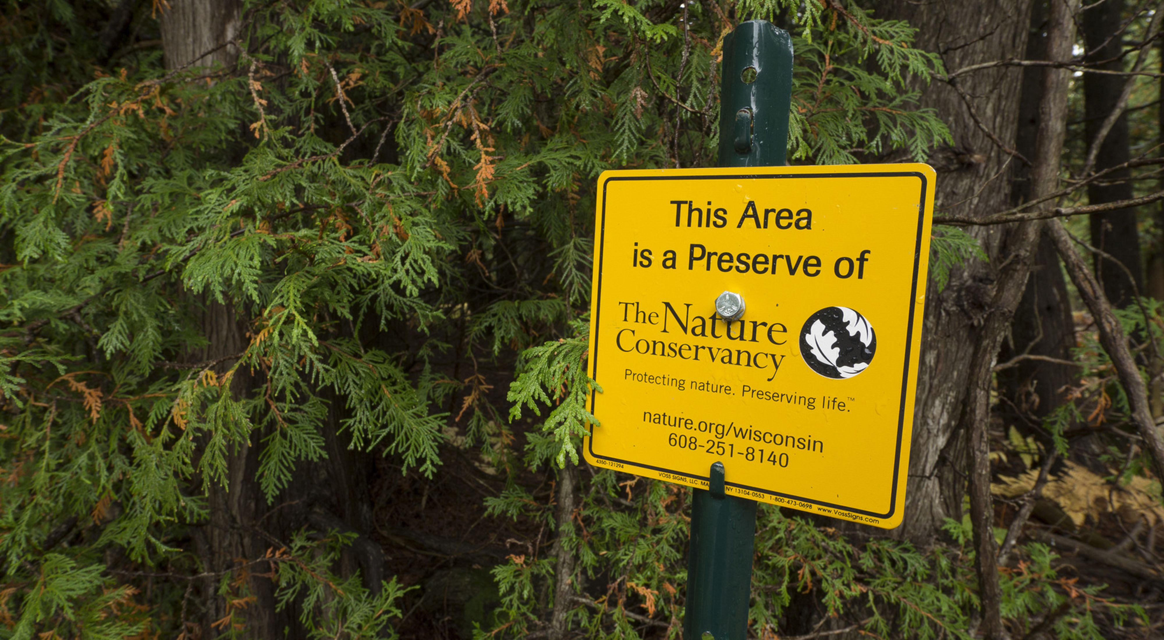 A sign that says this area is a preserve of The Nature Conservancy. Protecting nature. Preserving life. It also includes a vanity URL and a phone number.