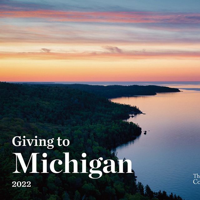 A colorful sunrise over the Keweenaw Peninsula in Michigan from a high vantage point. Text over the image: Giving to Michigan 2022. The Nature Conservancy. 