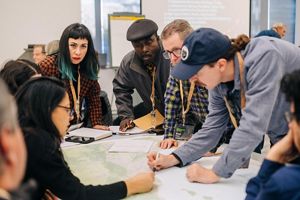 Symposium attendees leaning over a table. 