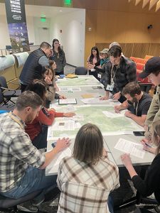 Symposium attendees leaning over a table. 