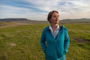 A portrait of a woman in a field staring off into the distance