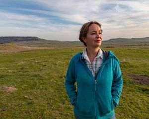 A portrait of a woman in a field staring off into the distance