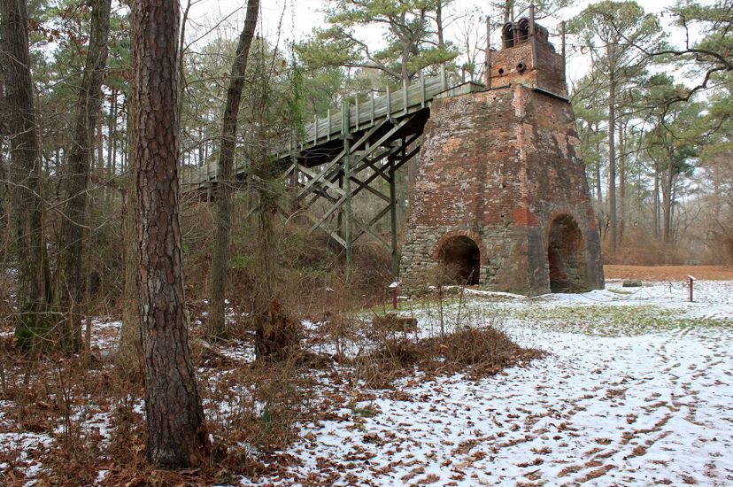 The remnants of a brick furnace tower over the snow covered ground.