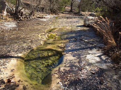 A small hole in a stream bed filled with clear water.