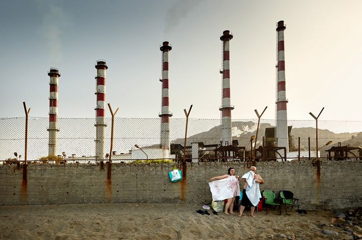The photo was taken in Greece. A huge factory broke into the sea, taking the beach away from restful people. A simple, ordinary scene is very symbolic for me.