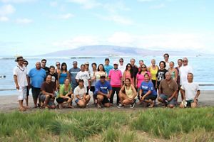 A large group poses for a photo in front of a coastline. 