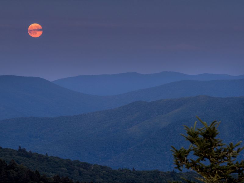 blue mountains with orange sun in the background