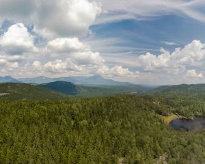 A view of a vast landscape of mountains surrounded by forest.