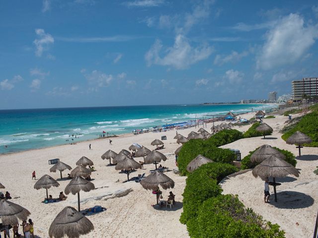 Cancun's famous turquoise blue water and white sand beach, with hotels in the distance.