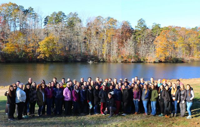 The Virginia chapter staff pose for a group photo outdoors in front of a narrow lake during a chapter retreat.