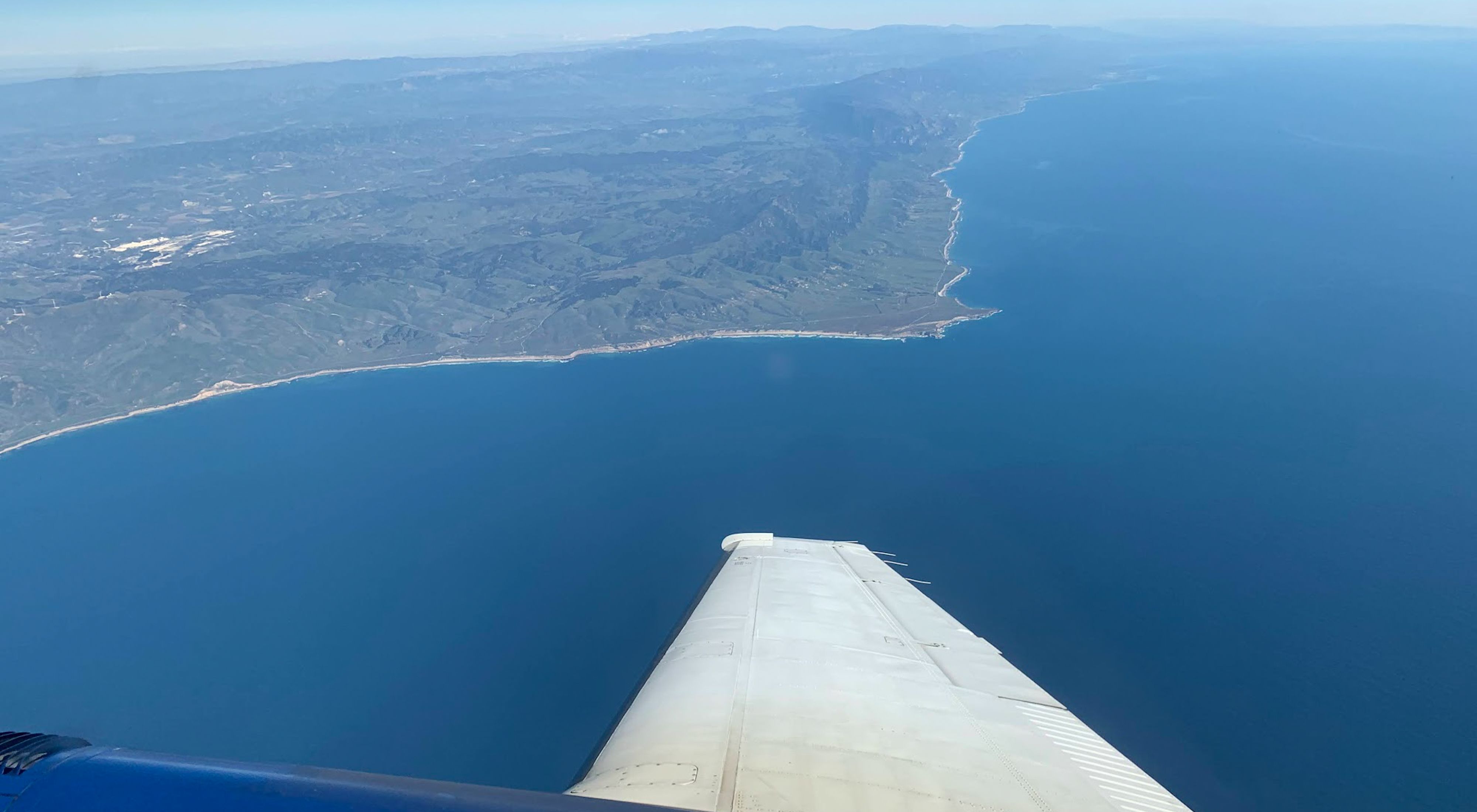 Looking out the window of a research plane collecting spectral imaging data of vegetation on land and in the ocean as part of the SHIFT campaign just off the Central Coast of California.