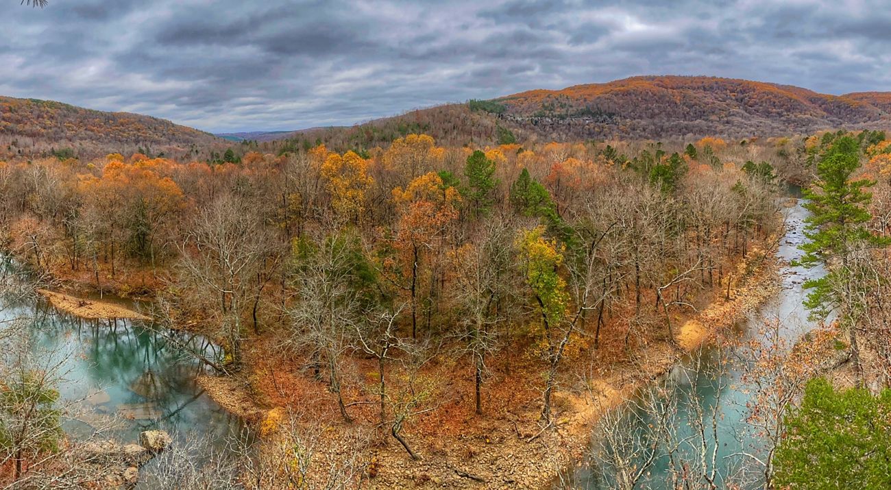 View from a high vantage point of a forest in fall colors with a river running alongside it.