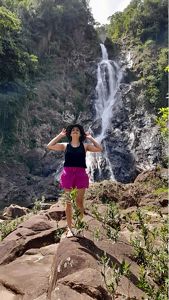 Diana Oviedo Vargas stands on rocks in front of a large waterfall.