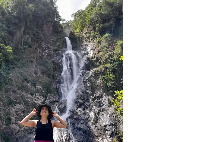 Diana Oviedo Vargas stands on rocks in front of a large waterfall.