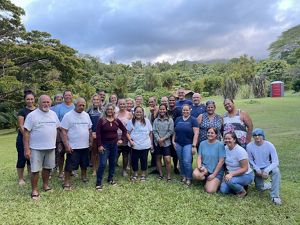 A group of people pose in front of a lush forest. 