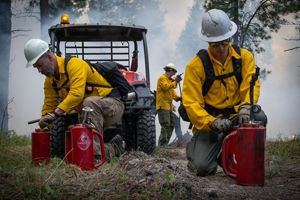 Two members of a Montana fire crew prepare drip torches for a controlled burn.