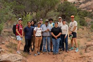 Several people stand together in a red-rock landscape and smile for the camera.