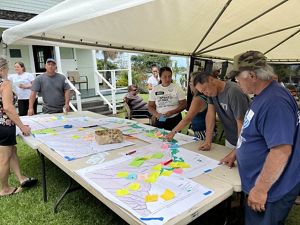A group of people look over maps covered in sticky notes. 