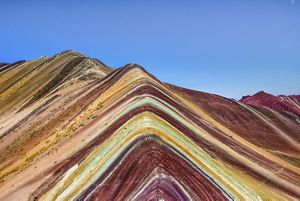 View of mountain peaks that appear to be striped with different colors of red, yellow, purple, green, and orange.