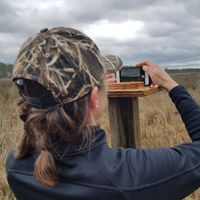 Resilient Coasts Program Director Jackie Specht positions her phone at a photo signpost at Robinson Neck Preserve, part of a long-term photo monitoring project.