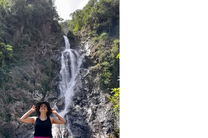Diana Oviedo Vargas stands on rocks in front of a large waterfall.