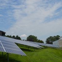 A ground solar panel beside a farm building.