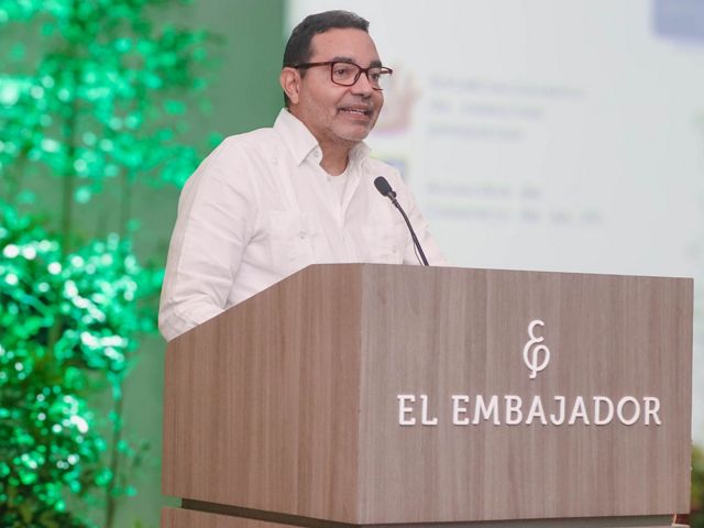 A man standing at podium speaks to a group.