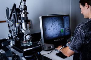 A person looks under a microscope at microfibers. 