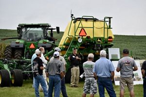 A group of people standing around a tractor in a field.