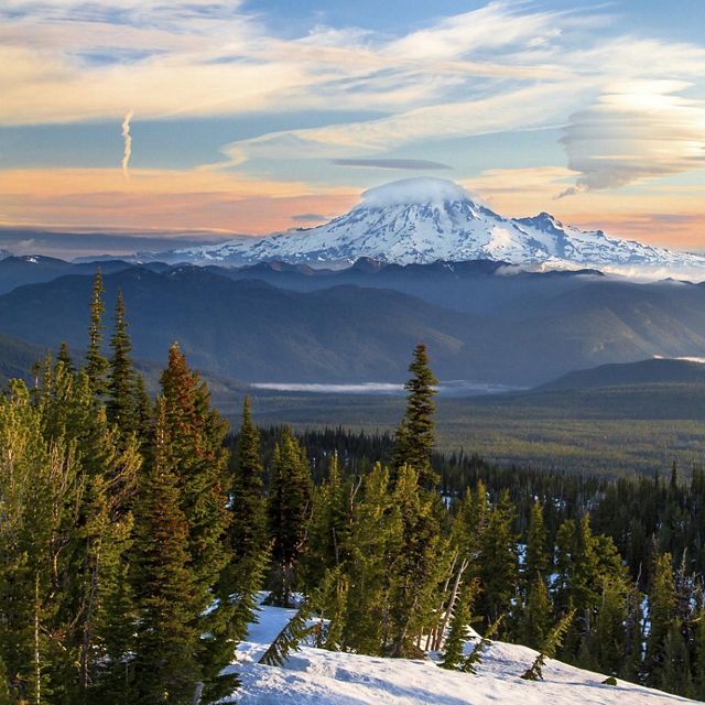 Mt. Rainier and Little Tahoma Peak are seen at sunrise with massive lenticular clouds above them—photographed from Mt. Adams.