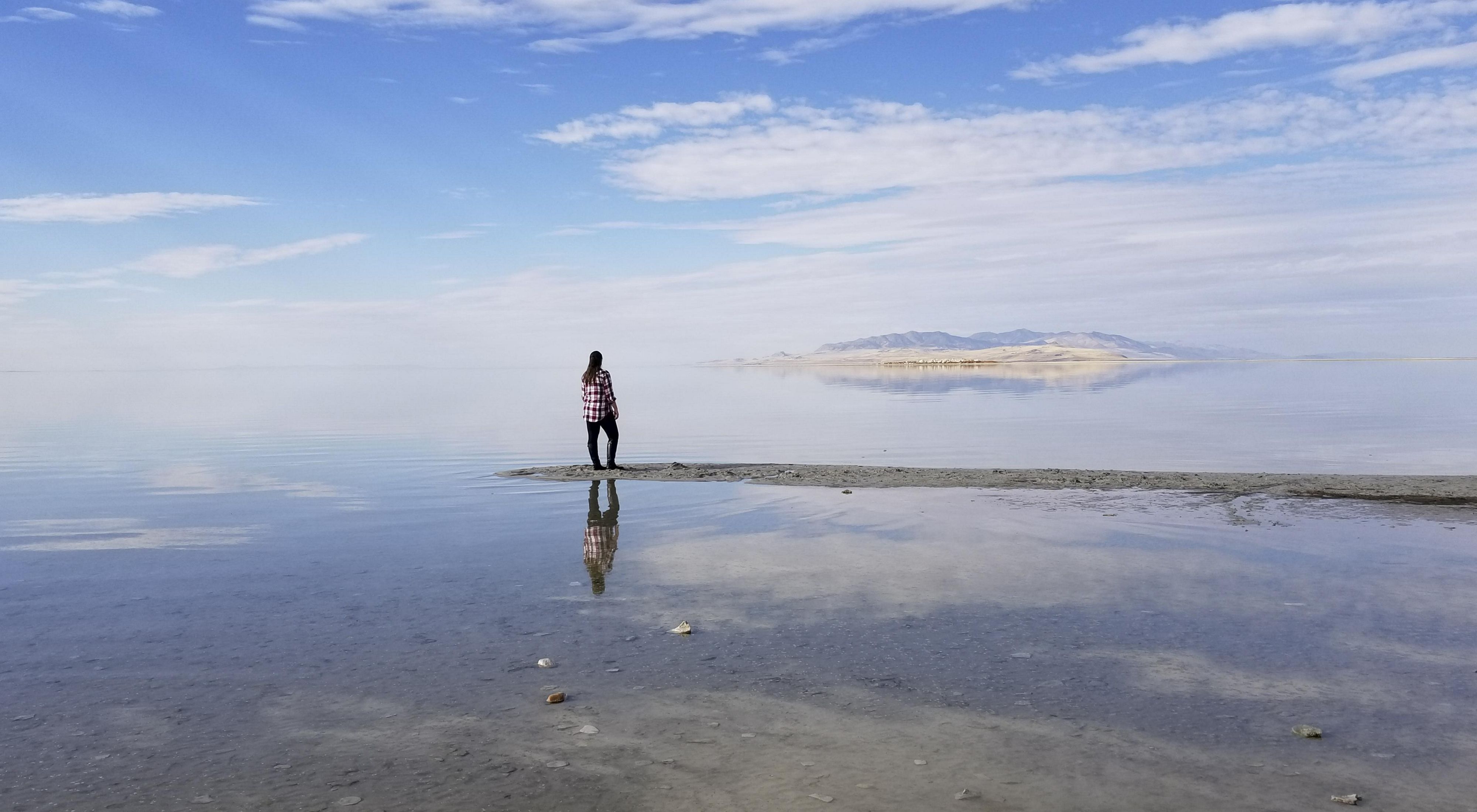 A person standing in the Great Salt Lake under a blue sky.