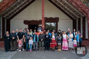 A group pf people together taking a picture under a high peaked roof.