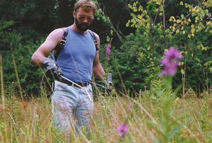 An old photograph of a person standing in a field spraying invasive species. 