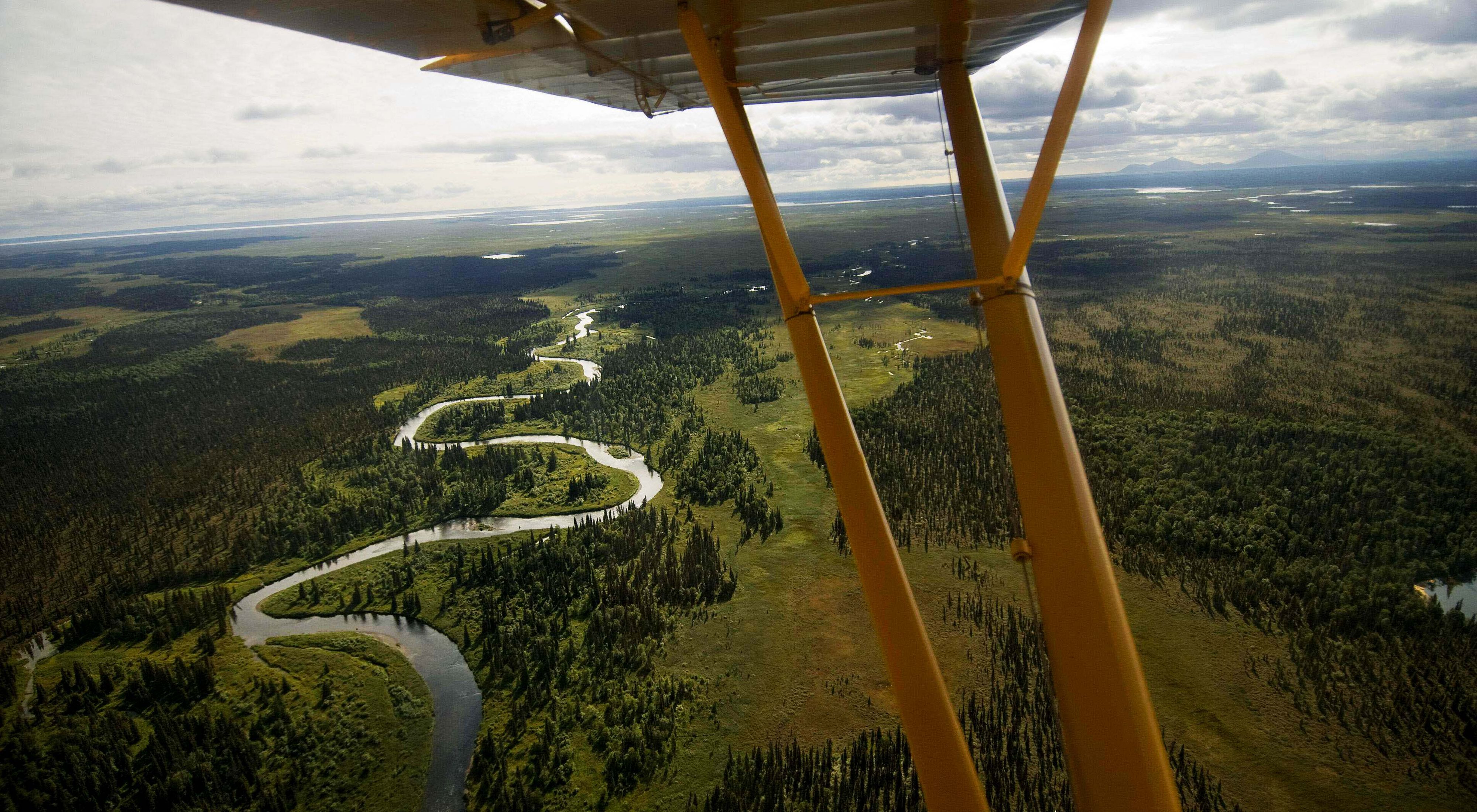 Photo taken from a bush plane showing the plane's yellow wings and Alaska's Bristol Bay below.