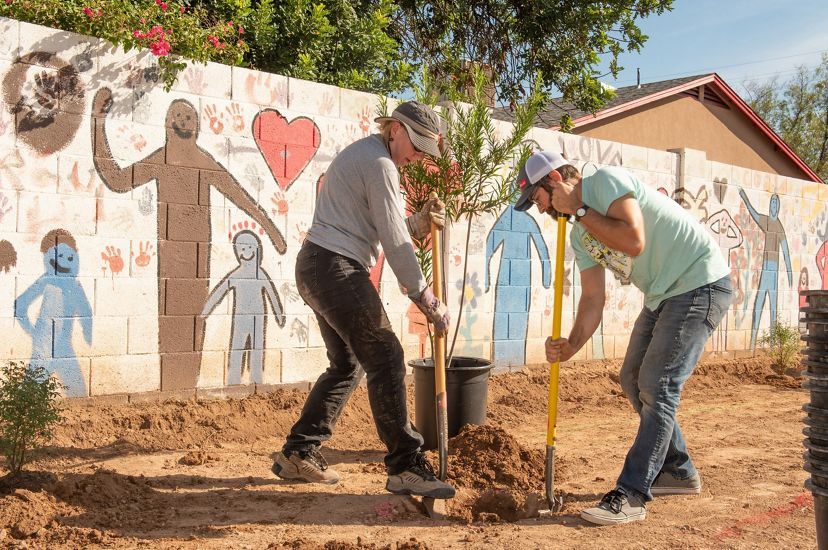 Two people dig a hole during an urban tree planting event. 