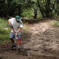 A volunteer holds a shovel while completing trail maintenance. 