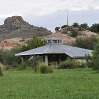 View of the visitor center building, which sits on a green lawn with mountains behind it.