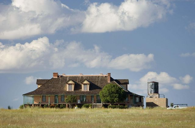 View of a ranch house on a sunny day with clouds above.