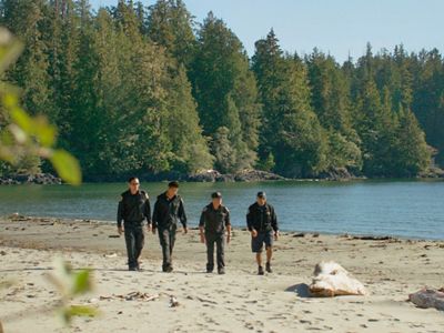 Four Ahousaht Watchmen walk across a beach in Canada.