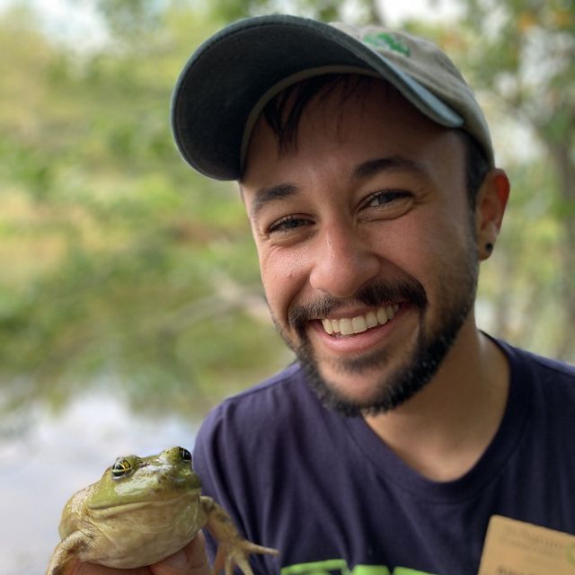Alex Navarro sonríe y sostiene una rana.