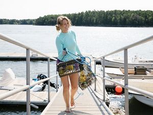 Amanda Moeser holds oyster cages on a dock.