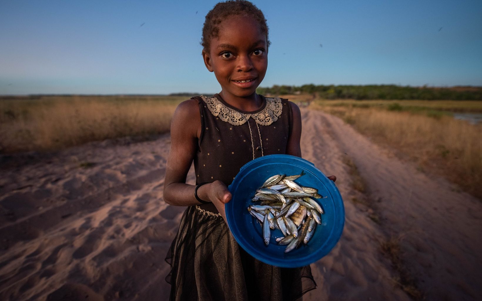 Young girl holding bowl of small fish