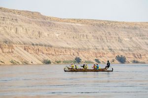 A group of people paddling through a river in a canoe.