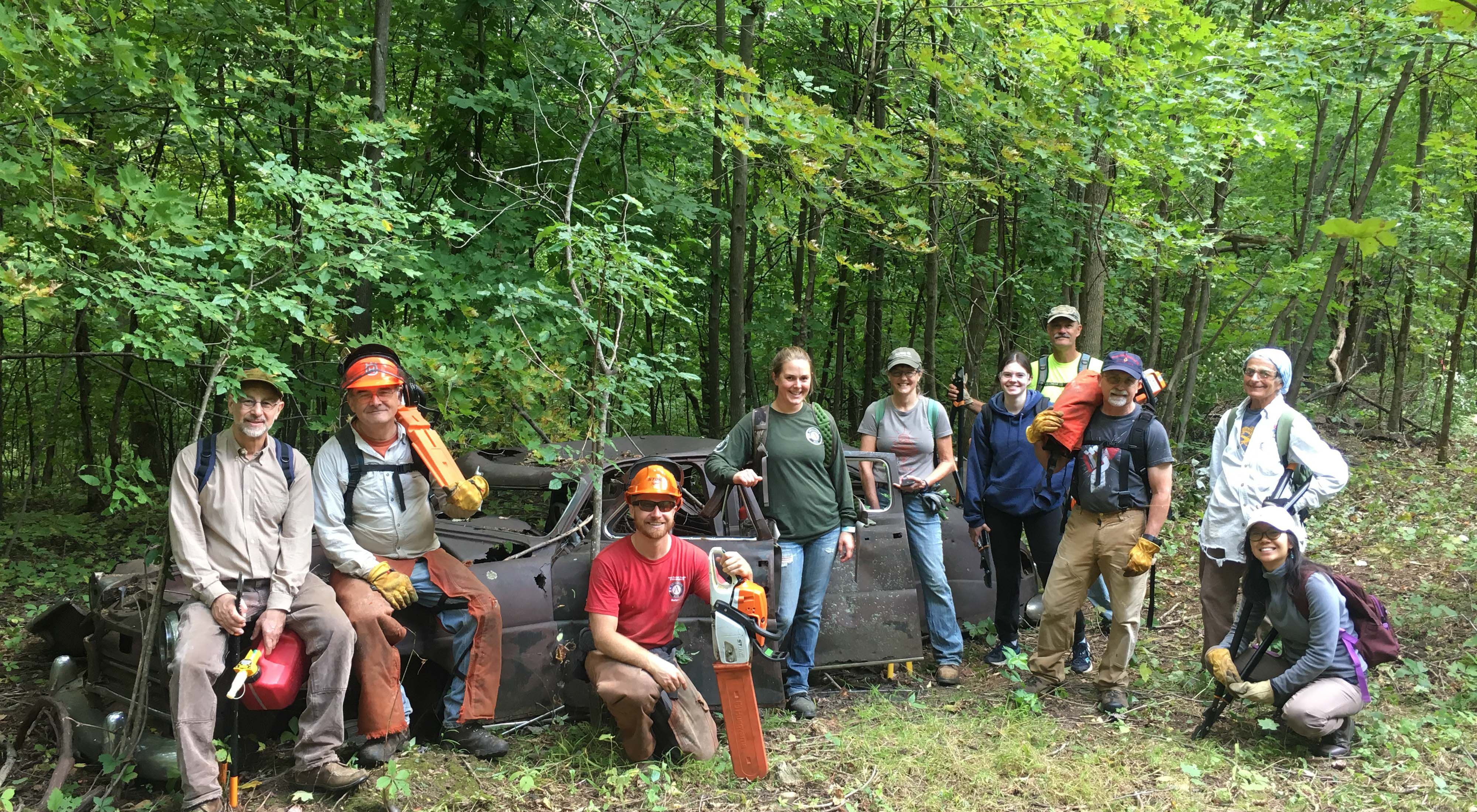 A group of TNC staff and volunteers standing with tools in a forest.
